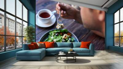 Man eating delicious salad while sitting at a bistro table Wall mural