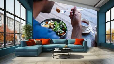 Man sitting at a bistro table eating delicious salad Wall mural