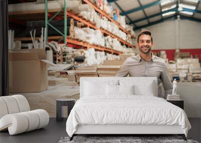 Manager smiling while leaning against stock in a large warehouse Wall mural