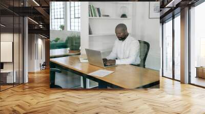 Manager working on a laptop at his office desk Wall mural