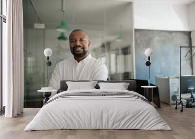 Smiling African American businessman standing alone in a large office Wall mural