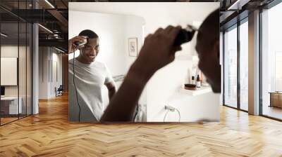 Smiling African man trimming his hair in his bathroom mirror Wall mural