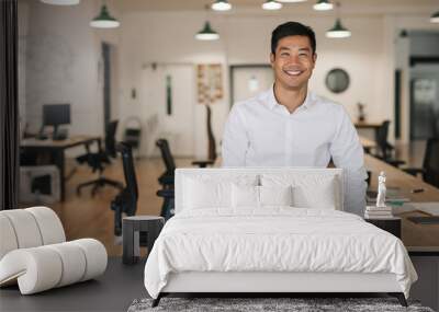 smiling asian businessman leaning on a table in an office Wall mural