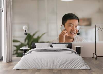 Smiling Asian businessman talking on a cellphone in an office Wall mural