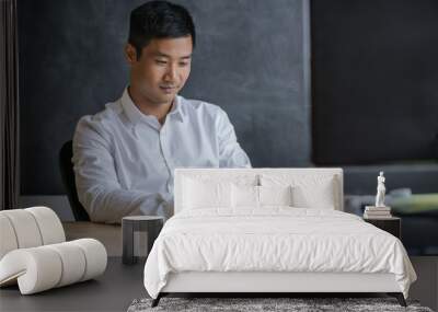 Smiling Asian businessman working on a tablet in an office Wall mural