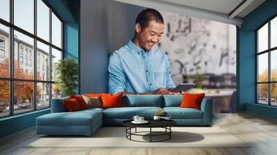 Smiling Asian designer using a tablet in a modern office Wall mural