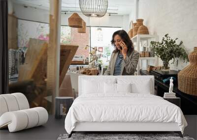 Smiling Asian woman talking on a cellphone in her store Wall mural