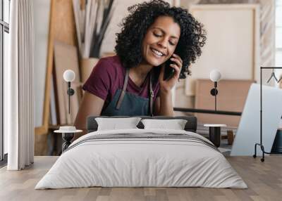 Smiling entrepreneur talking on the phone in her framing studio Wall mural