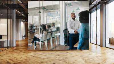 Smiling office manager shaking hands with a staff member Wall mural