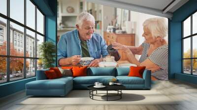 Smiling senior woman pouring her husband a coffee over breakfast Wall mural