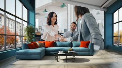 Smiling young businesswoman shaking hands with an office colleague Wall mural