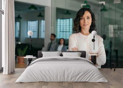 Smiling young businesswoman standing confidently in a large office Wall mural