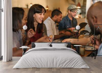 Smiling young friends enjoying dinner together in a trendy bistro Wall mural