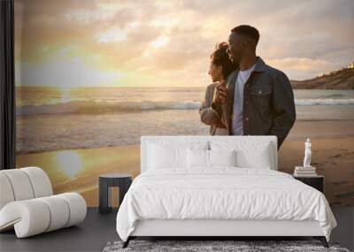 Smiling young multiethnic couple watching the sunset on a beach Wall mural