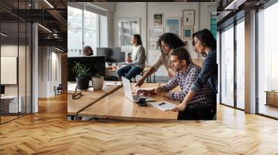 Three young designers using a laptop together at work Wall mural