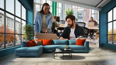 Two diverse young businesspeople working together on a laptop Wall mural