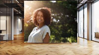 Woman standing in a park in the summer and smiling Wall mural