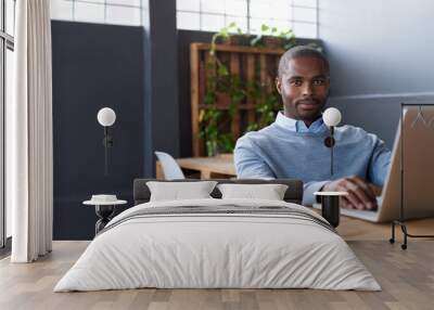 Young African businessman working on a laptop in an office Wall mural