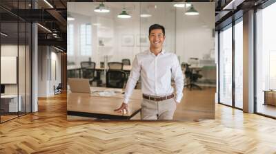 young asian businessman standing in an office smiling confidently Wall mural