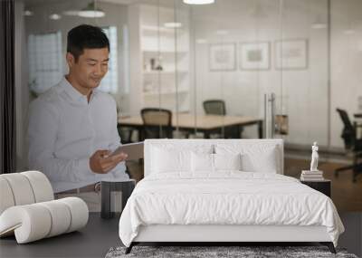 Young Asian businessman using a tablet in an office Wall mural