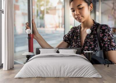 young asian businesswoman riding on a city train reading texts Wall mural