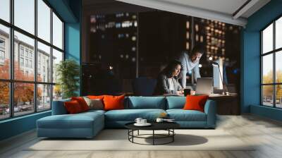 Young business colleagues working overtime together at an office desk Wall mural