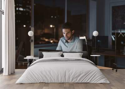 Young businessman working late at night in an office Wall mural