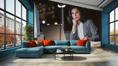 Young businesswoman looking tired while working overtime in an office Wall mural