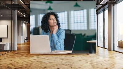 young businesswoman thinking while using a laptop at work Wall mural