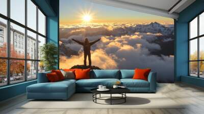 Person standing on mountain peak above clouds at sunrise with arms outstretched. Wall mural