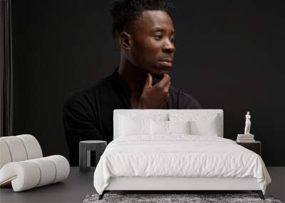 portrait of an African young man in a black shirt on a black background Wall mural