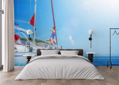 Girl jump in sea of sailing yacht on summer cruise. Travel adventure, yachting with child on vacation. Wall mural