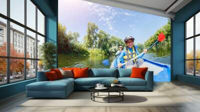 Happy boy kayaking on the river on a sunny day during summer vacation Wall mural