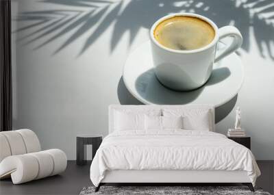 Coffee, espresso in a white coffee cup on a white table under shade of palm leaves. Black coffee and palm tree shadows on a light grey background Wall mural