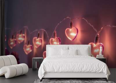 Garland with pink hearts. String of heart shaped lights hanging on a wall. Pink Valentines. Abstract love background. Decoration for Valentine's Day or Christmas Wall mural