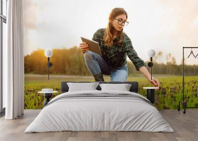 A woman farmer with a modern tablet in green field. Innovative smart farm system technology, agricultural management. Wall mural