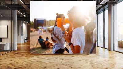 Beach party. Two young woman with beer at music festival. Summer holiday, vacation concept. Wall mural