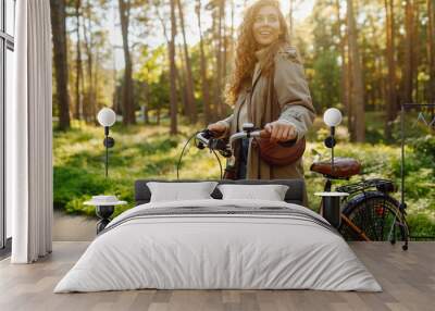 Beautiful happy woman riding bicycle in park. Woman enjoys nature. Active day. Wall mural