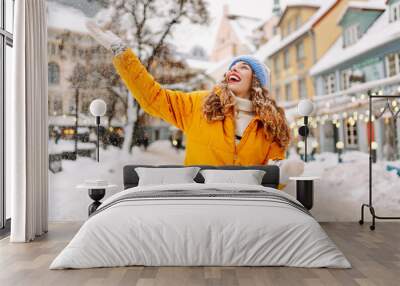 Beautiful woman playing with snow on winter street. Concept of walks, weekends. Winter holidays Wall mural