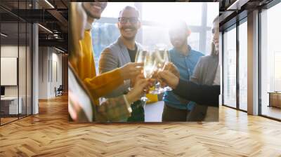 Business people celebrate with glasses of champagne in the office at a corporate event. A group of young people are having fun in the office. Holidays, business concept. Wall mural