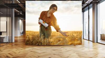 Farmer woman checking wheat field progress in a wheat field. Harvesting. Agro business. Wall mural