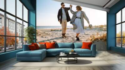 Fashion couple enjoying each other on beach during autumn sunny day. Travel, weekend, relax .and lifestyle concept.  Wall mural