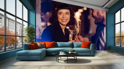 Happy loving couple enjoying having drinks together at the bar. Young man and woman clinking a glass champagne, enjoying winter holiday. Party, celebration, drink, birthday concept. Romantic evening. Wall mural