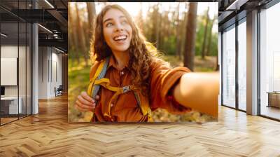 Happy woman tourist taking picture of herself while walking in a sunny forest.  find the route. Travel blog. Adventure, vacation. Wall mural