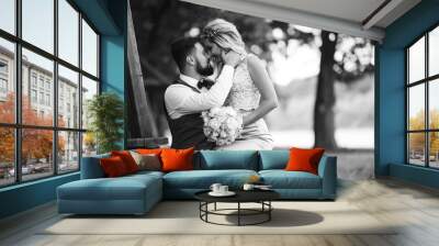 Sensual Black and white foto of bride and groom. Stylish couple of happy newlyweds posing and kisses in the park on their wedding day. Together. The concept of youth, love, fashion and lifestyle.  Wall mural