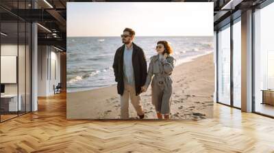 Stylish couple walking and hugging by the sea. Lovely hipster couple enjoying time together. The concept of youth, love and lifestyle. Springtime. Wall mural