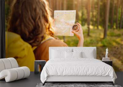 Traveler young woman searching direction with a compass on background of map in the forest. Adventure, vacation concept. Active lifestyle Wall mural