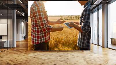 Two young farmers standing in wheat field examining crop holding tablet using internet. Modern agriculture technology. Smart farming concept.  Wall mural