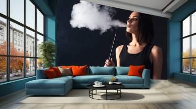 Young, beautiful girl smokes a hookah. It produces smoke from his mouth. Business style clothing. The pleasure of smoking.


 Wall mural