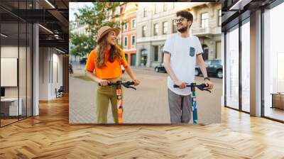 Young couple having fun driving electric scooter through the city. Active life. Ecological transportation concept. Wall mural